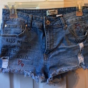 Denim shorts . Frayed bottom . Words on shorts